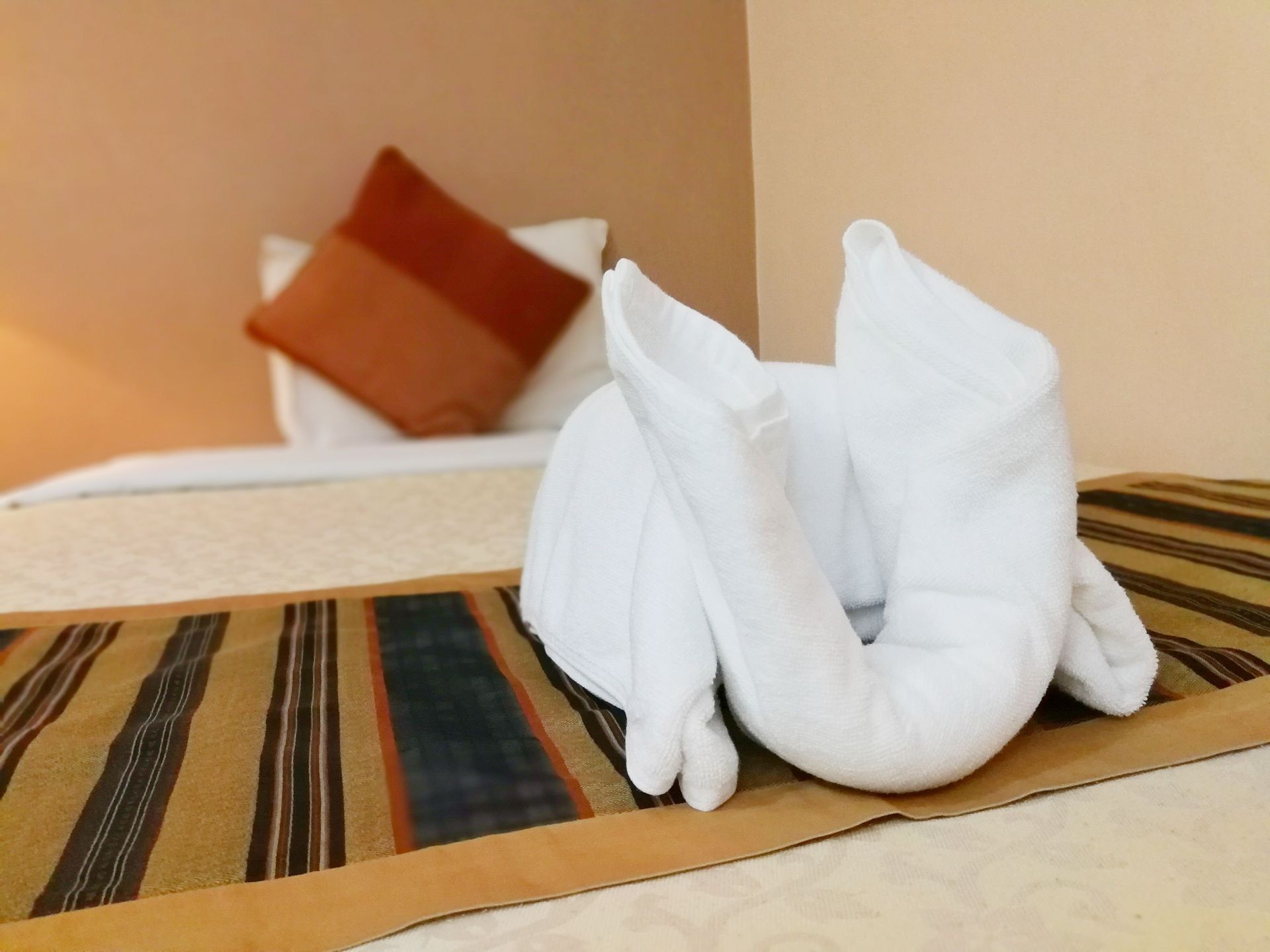 Close-up of fresh white bath towels on the bed sheet. Room service maid cleaning hotel room. 